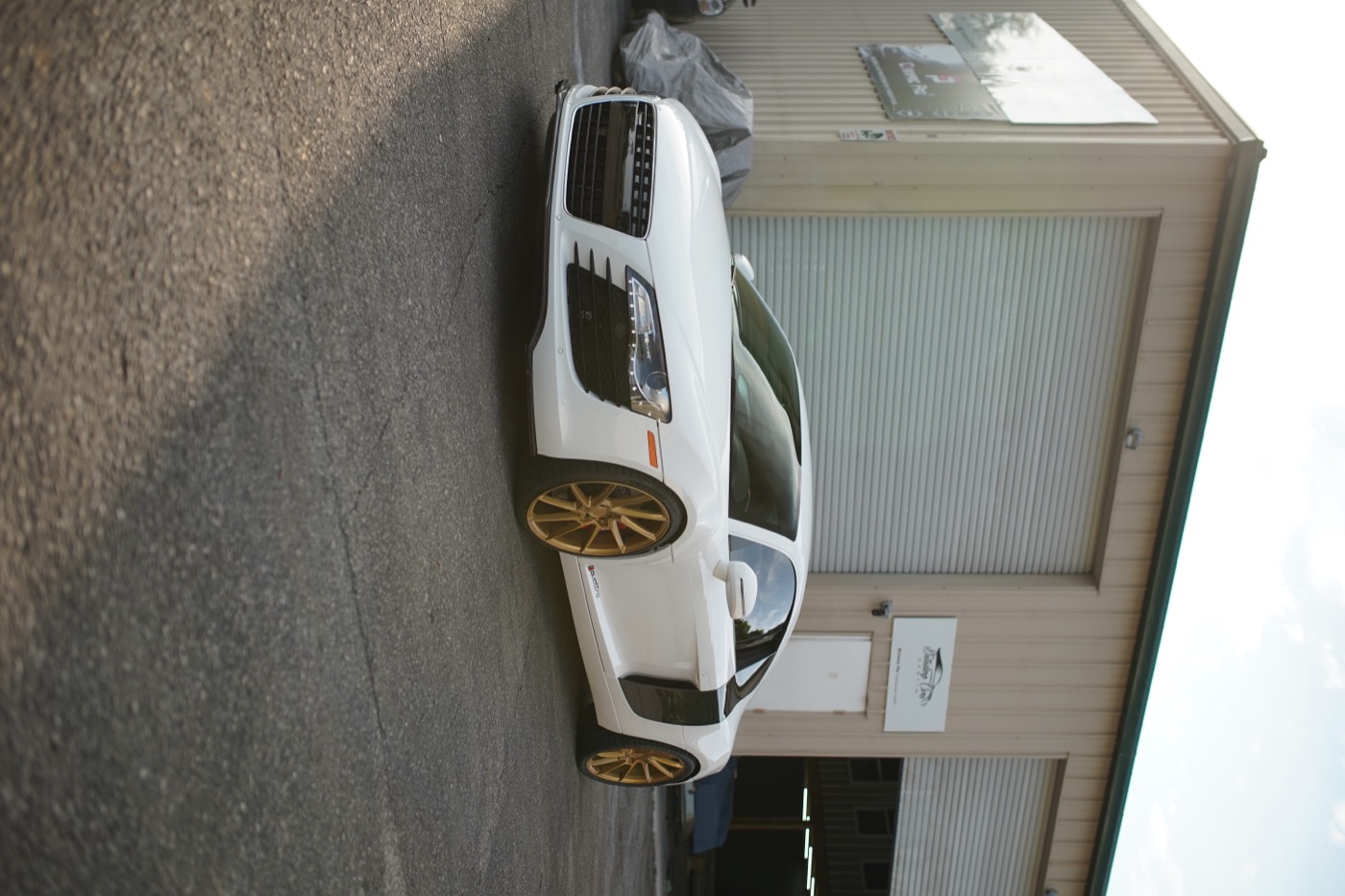 White Audi R8 with gold wheels outside the shop