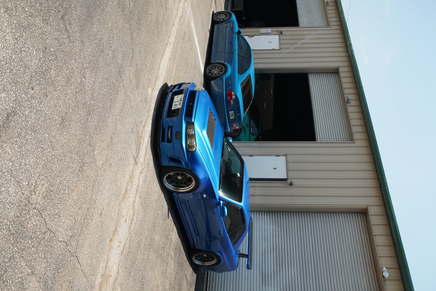 Pair of blue BMW M cars outside the shop